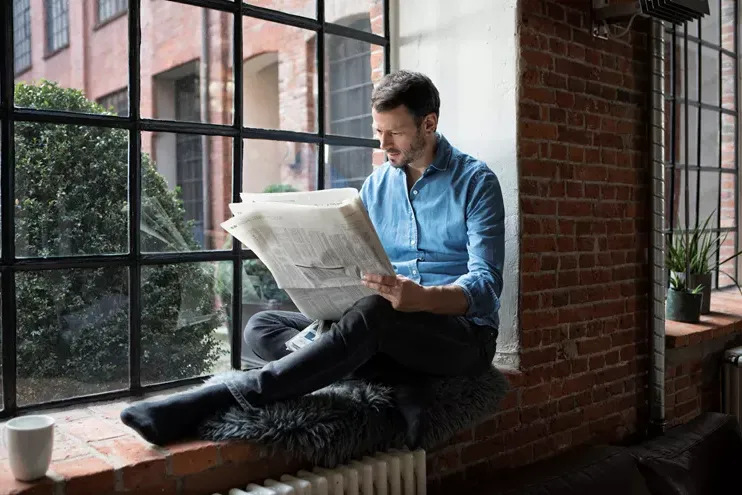 一个人坐在窗台上看报纸
